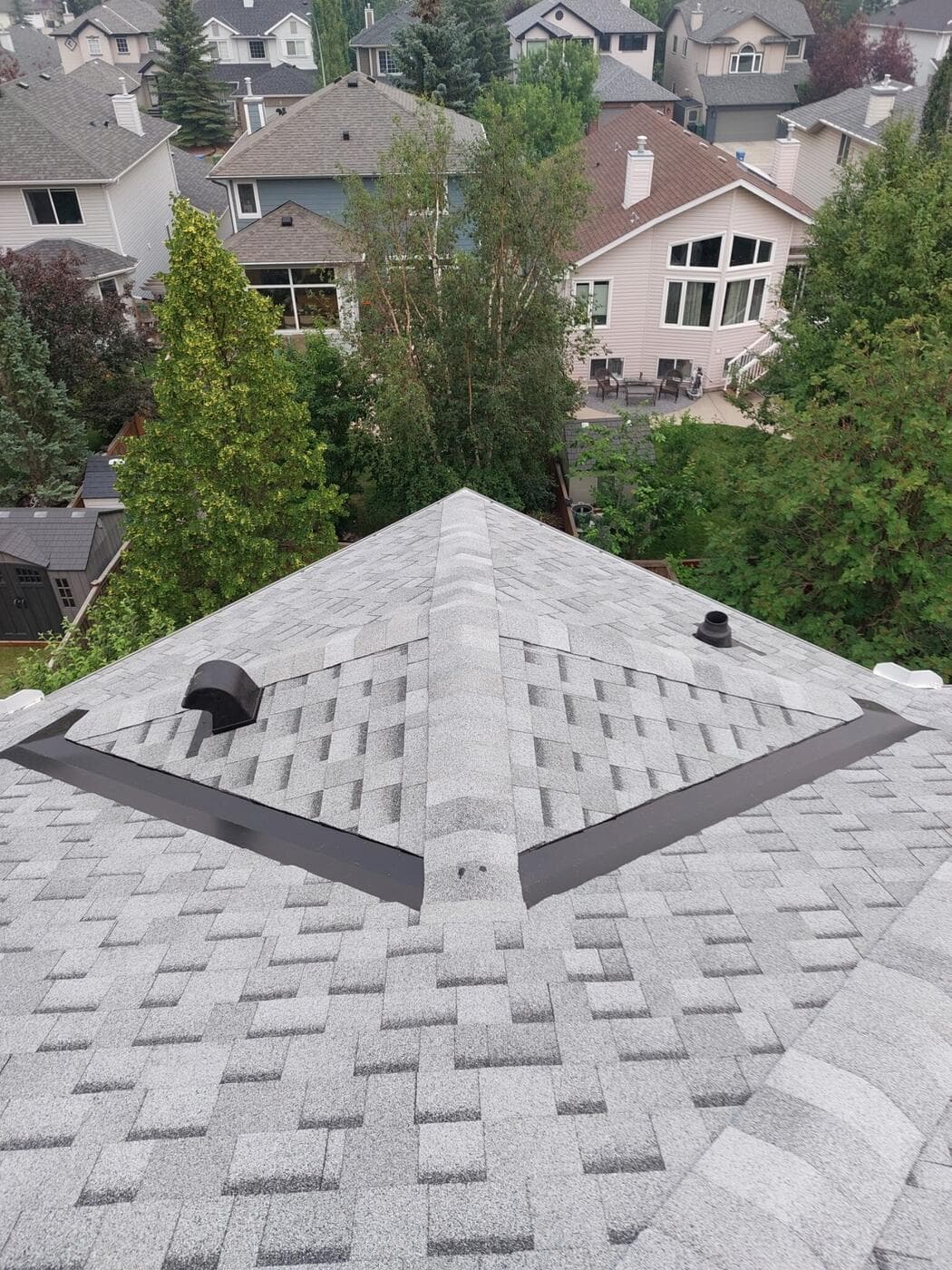 A finished asphalt shingle roof on a Calgary home, hip roof with clean ridge lines