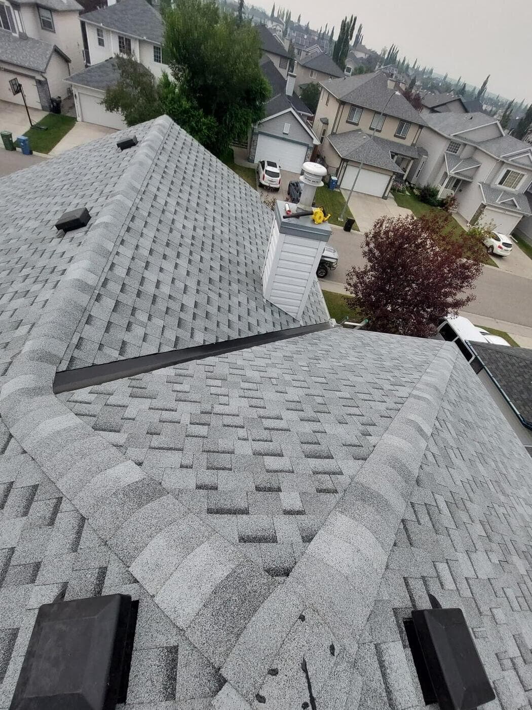 View across a Calgary residential street from a roof, neighbouring homes visible