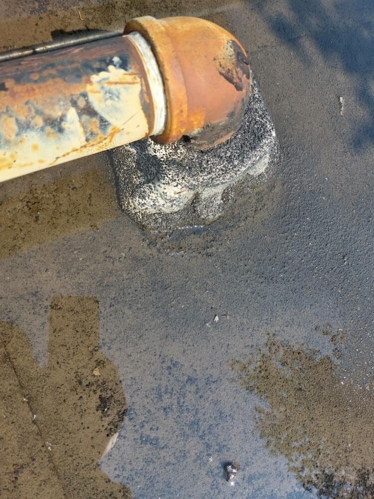 Corroded pipe penetration sitting in ponded water on a flat roof