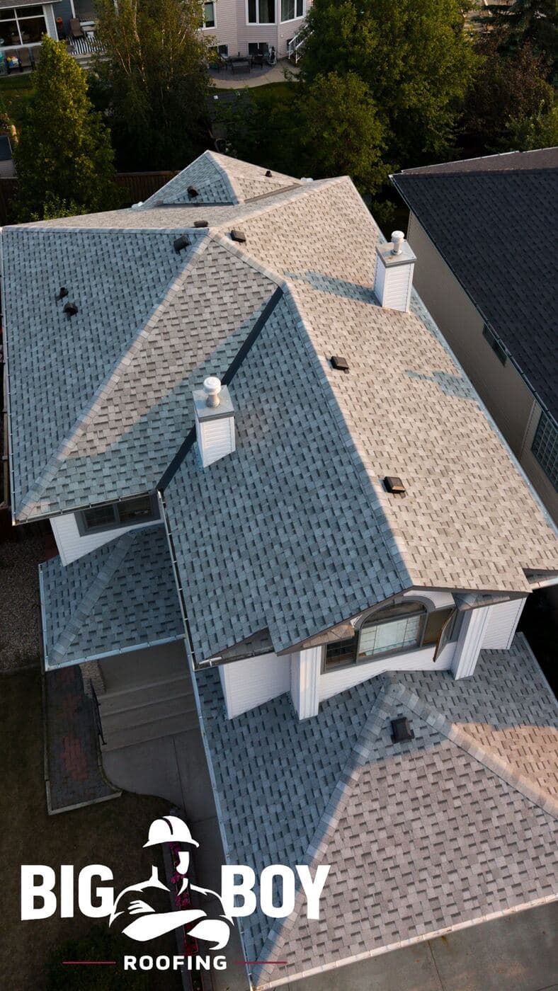 Overhead view of a completed asphalt shingle roof on a two-storey Calgary home, new ridge caps and vents throughout