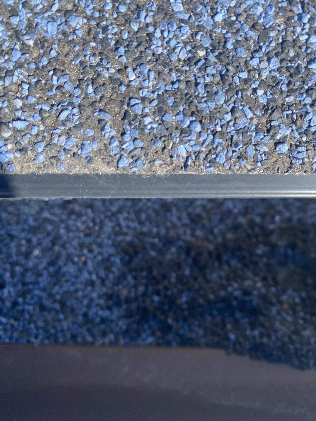 Loose shingle granules collected along a Calgary roof edge after hail