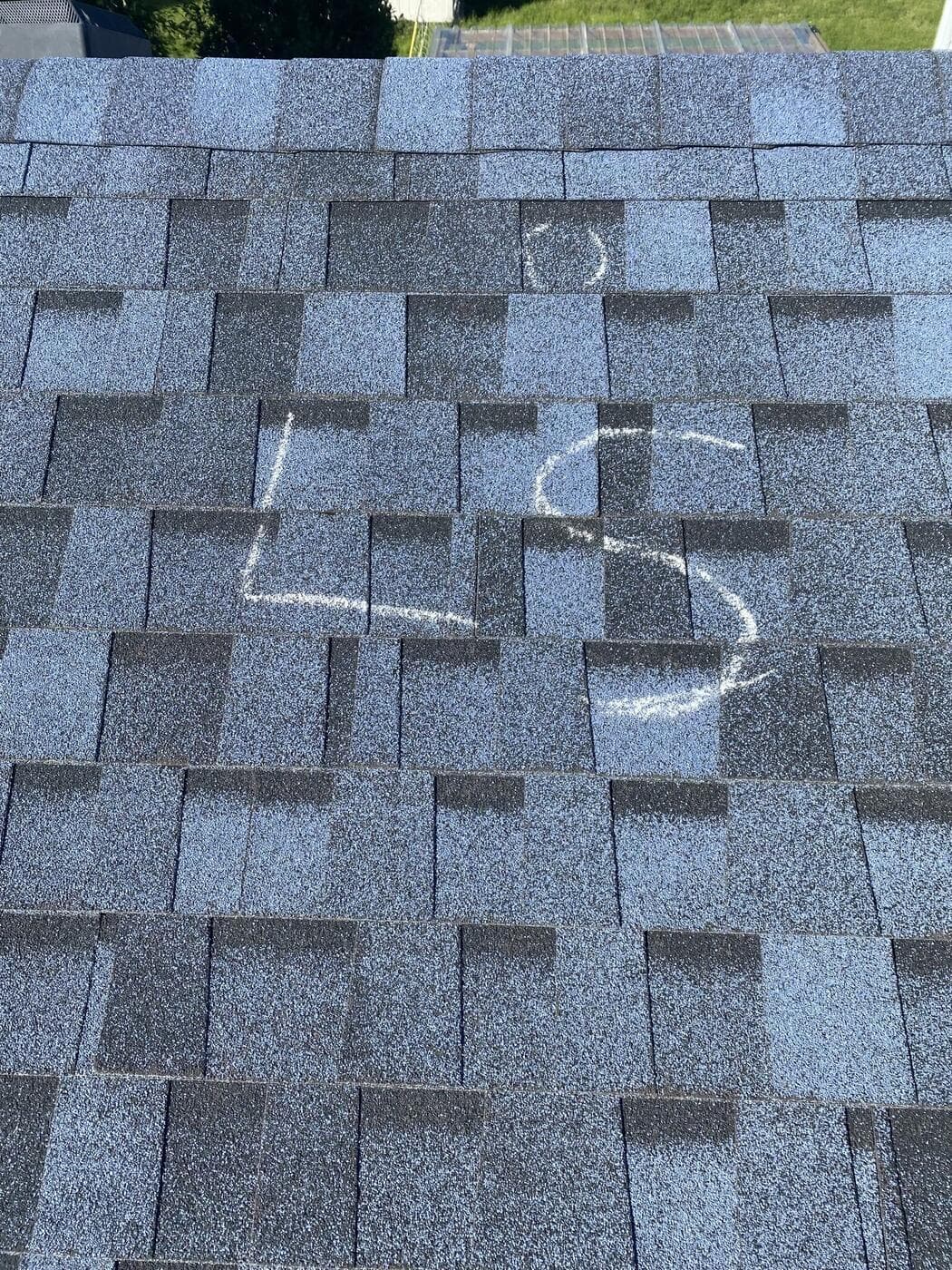 A roof slope chalk-marked with its elevation letter during a hail inspection