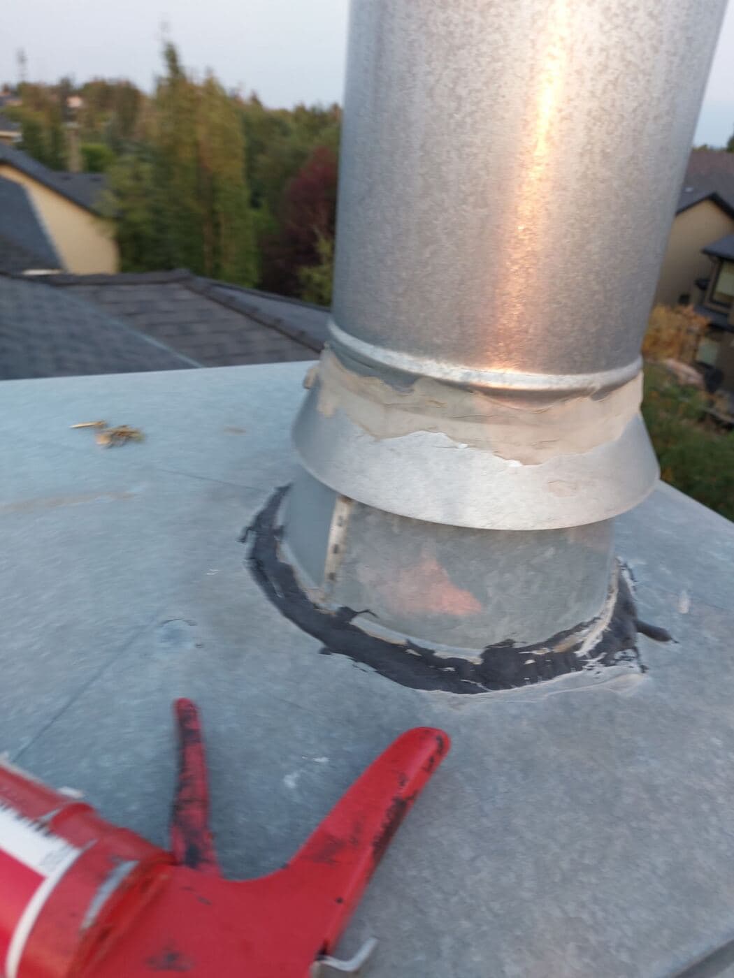 Cracked and failed sealant around a metal vent stack on a Calgary roof