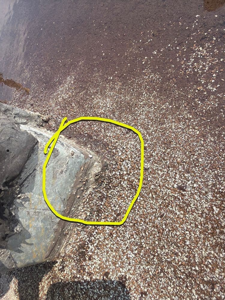 Failed curb flashing on a commercial flat roof, marked in chalk for the report