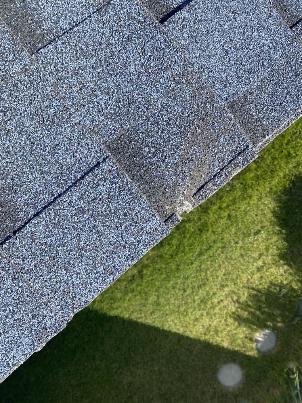 Hail impact circled in chalk on an architectural shingle
