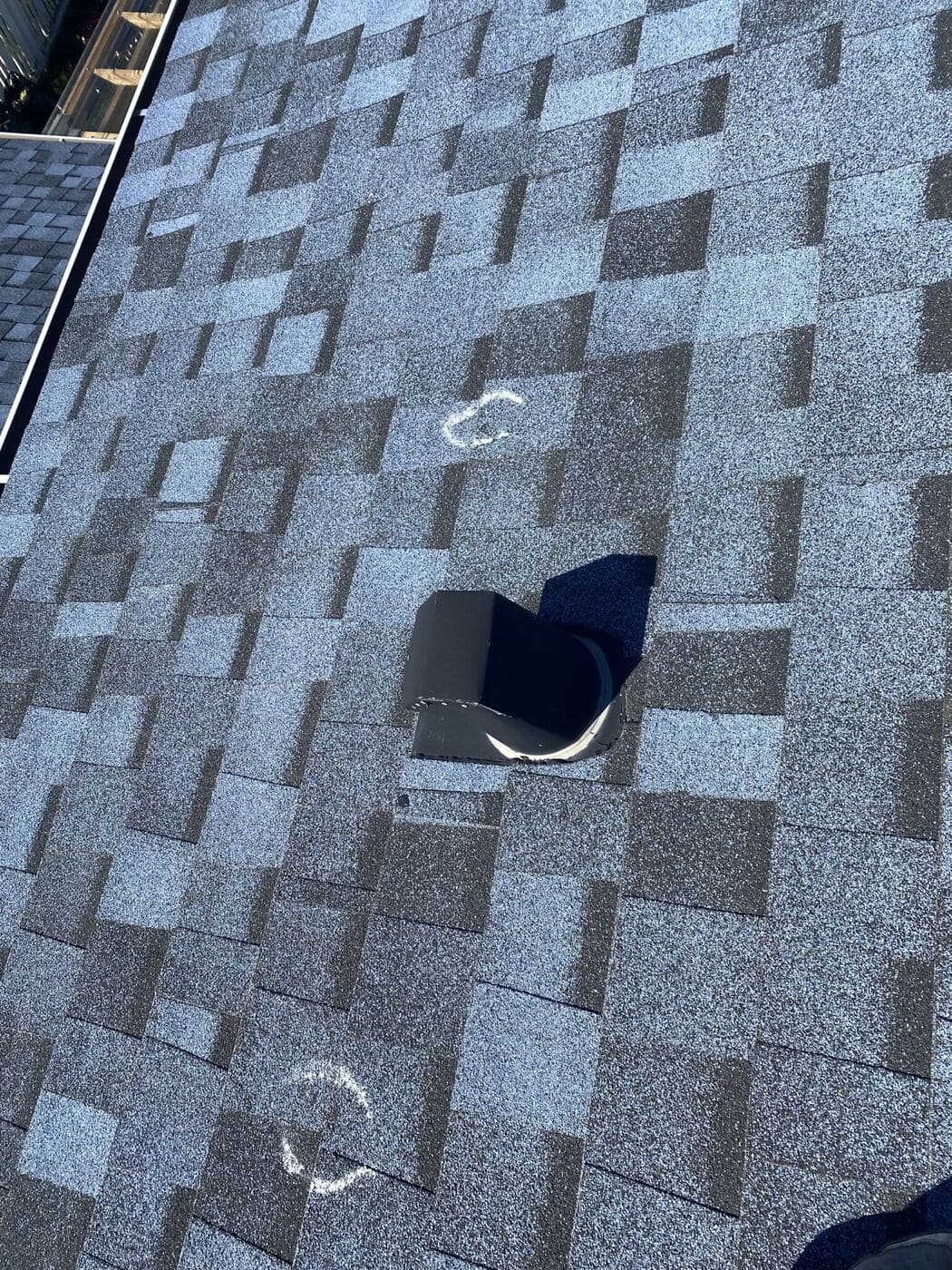 Damaged roof vent with hail impacts chalked on the surrounding shingles