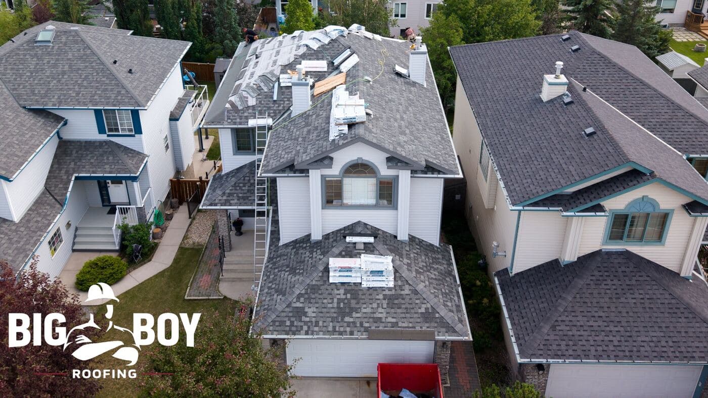 Aerial view of an NW Calgary roof replacement in progress, shingle bundles staged across the slopes